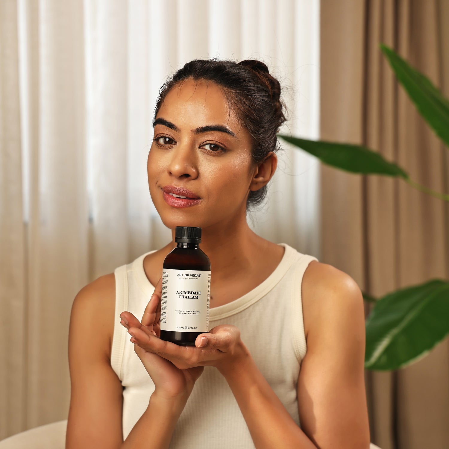 Art of Vedas Arimedadi Thailam - Woman Holding Ayurvedic Oil for Traditional Dental and Oral Care