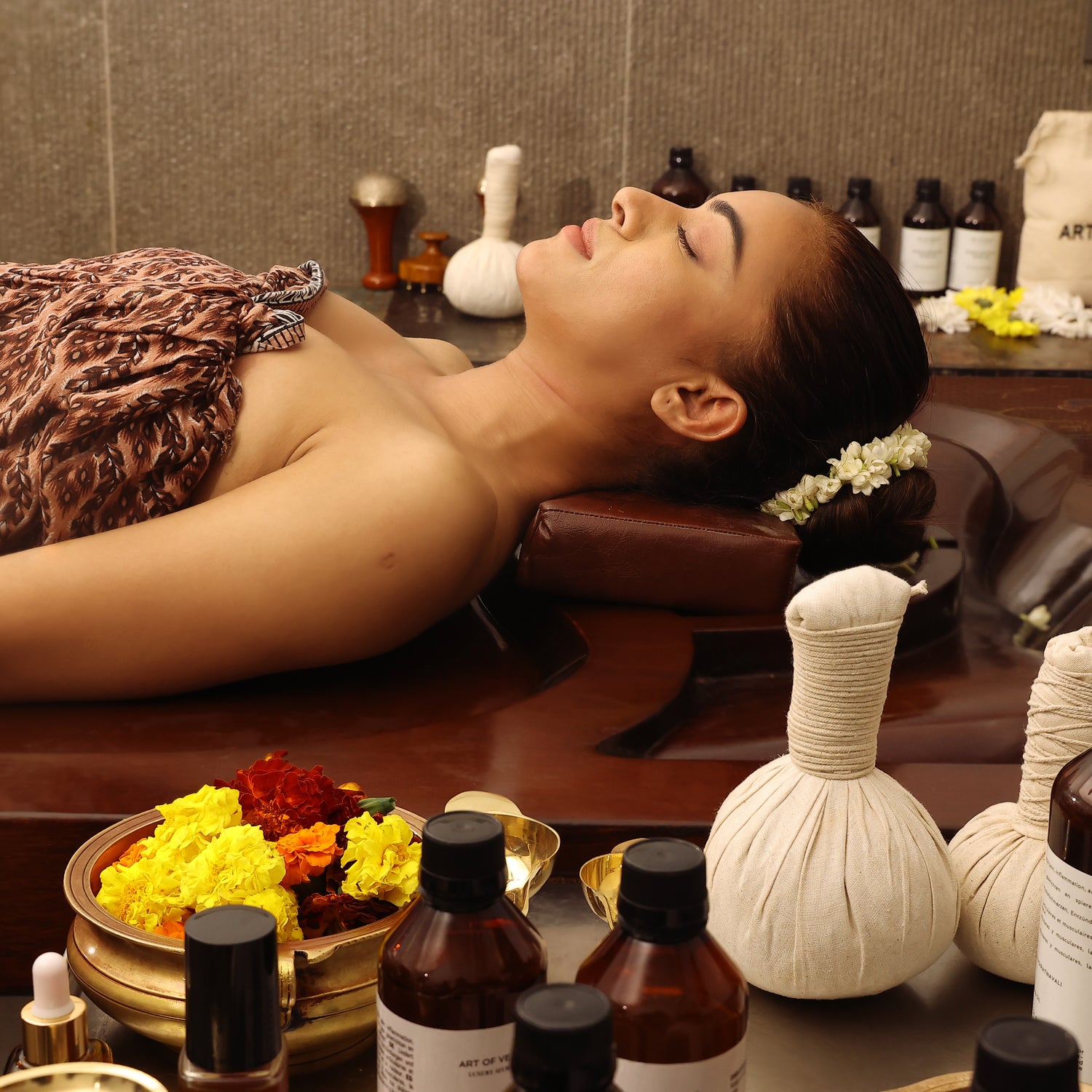 Ayurvedic spa treatment setting with herbal compress balls, essential oils, and flowers - Shop Ayurveda in Europe by Art of Vedas